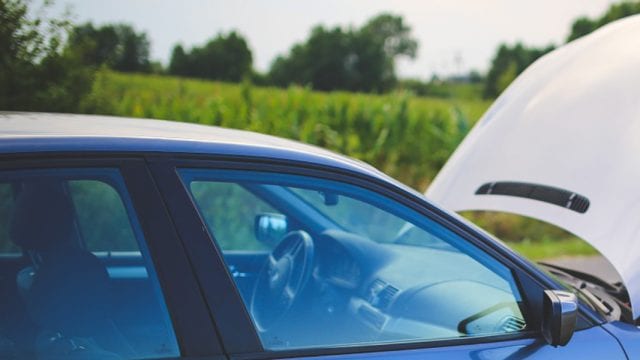 person looking underneath the hood of a car